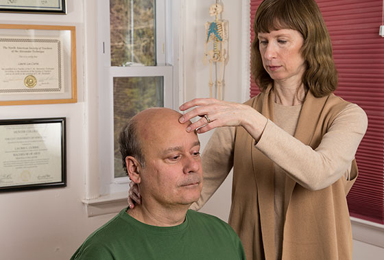 Certified Alexander Technique teacher Laurie Currie, Mahopac NY Certified Alexander Technique teacher Laurie Currie working with student's head/neck balance while seated in chair in Mahopac, New York.